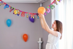 Happy preteen girl hanging up balloons decorating house preparing to birthday party. Happy birthday string.